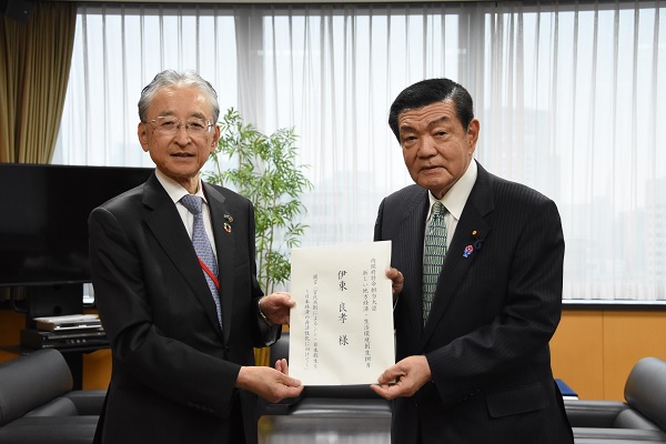 伊東大臣(右)に要望を手交する斎藤総合政策委員長(左)