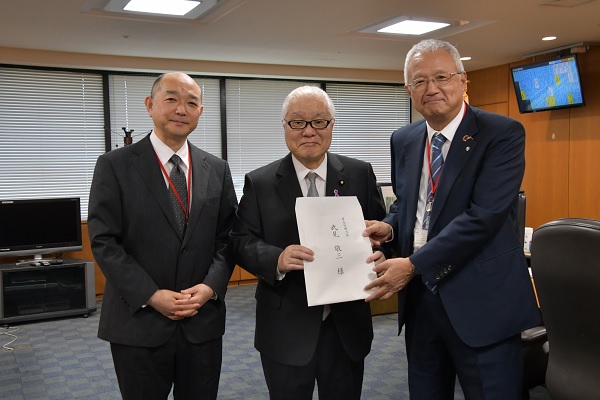 武見大臣（中央）に提言を手交する中山委員長（右）、藤井共同委員長（左）