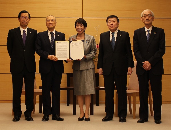 採択された共同声明を手に持つ高市首相（中央）と広瀬委員長（中央左）