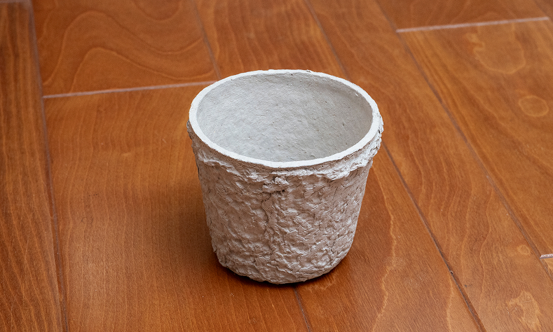 花屋などで廃棄される茎と新聞古紙、水を原料にした日本初のサーキュラーエコノミータイプの植物用ポッド。土に埋めると、やがて土に還る