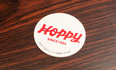 「ホッピー」の製造工程で発生する麦芽の搾りかすをすき込んで作られた紙をコースターに。ホッピービバレッジとの意欲的なコラボレーション