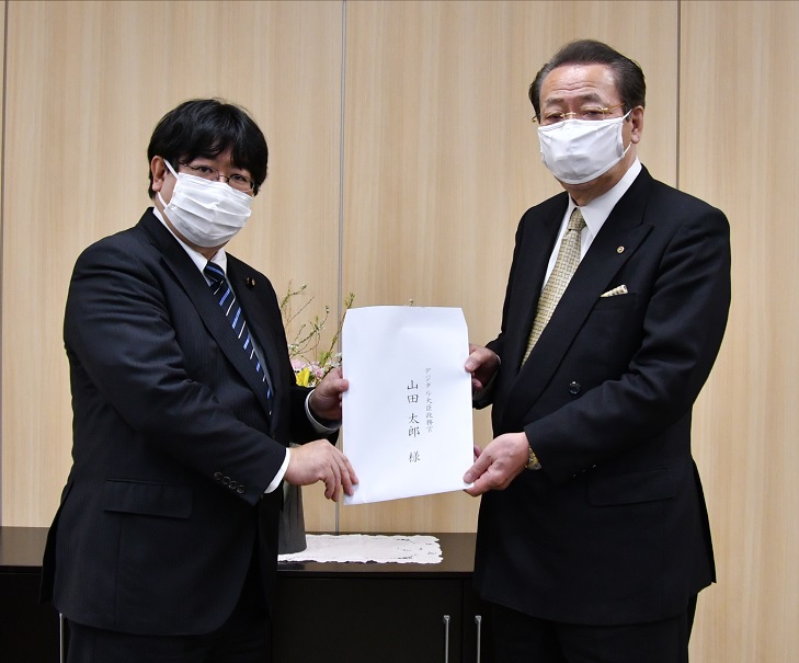山田デジタル大臣政務官（左）に意見を手交する金子委員長